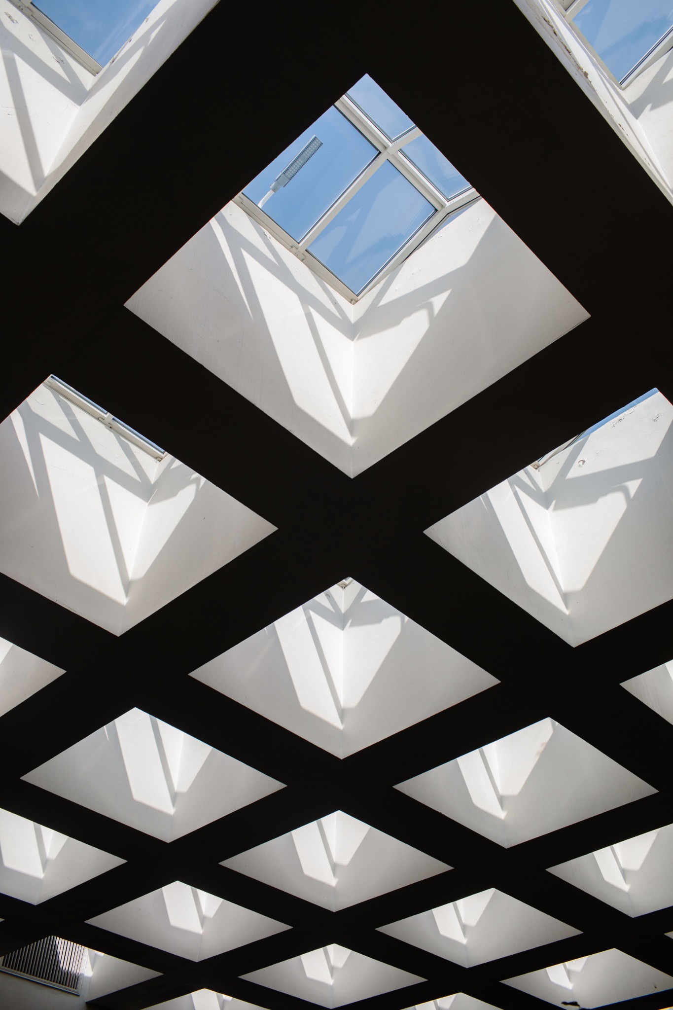Architectural beams framing bright skylights and blue sky