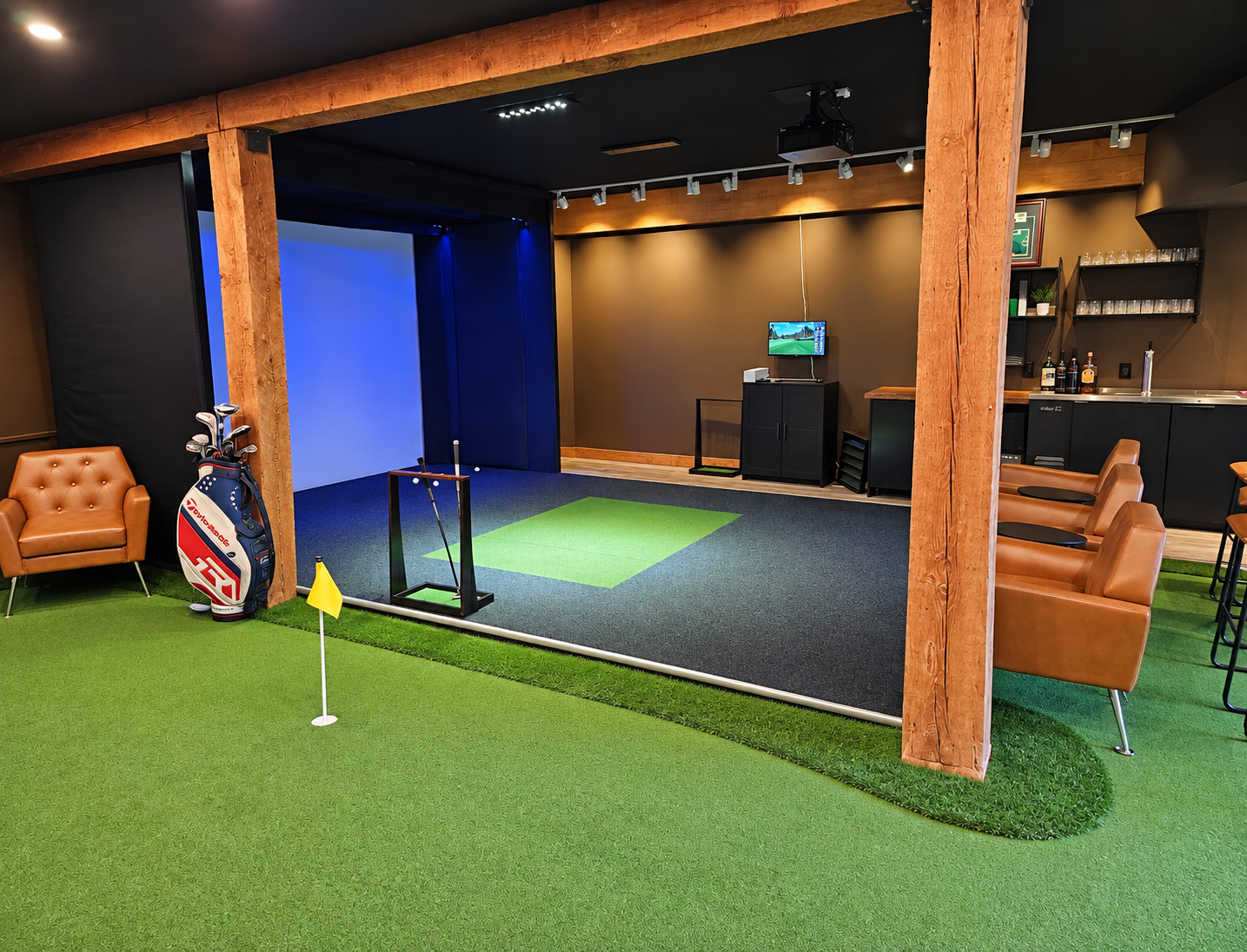 Indoor golf simulator with putting green, timber beams, lounge seating, and bar